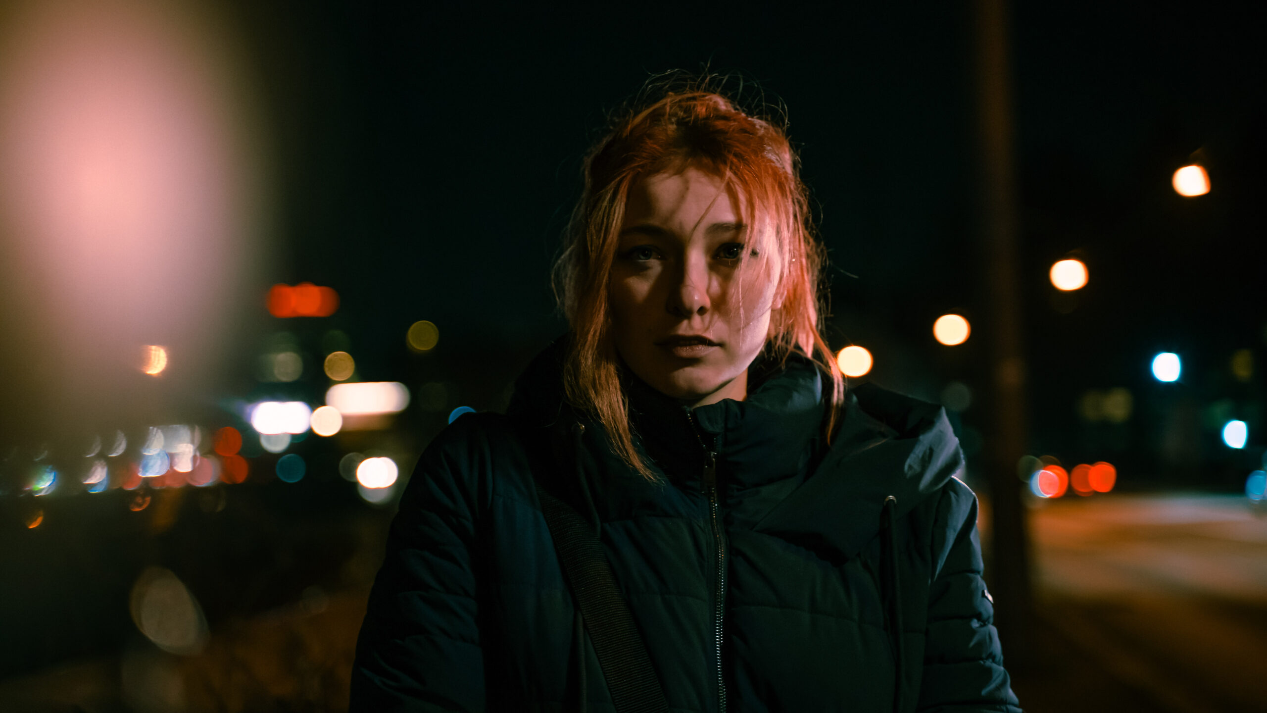 Jorinde Fritsch steht auf einer Straße bei Nacht. Das Filmstill ist sehr düster und nur die Person ist wirklich im Fokus.